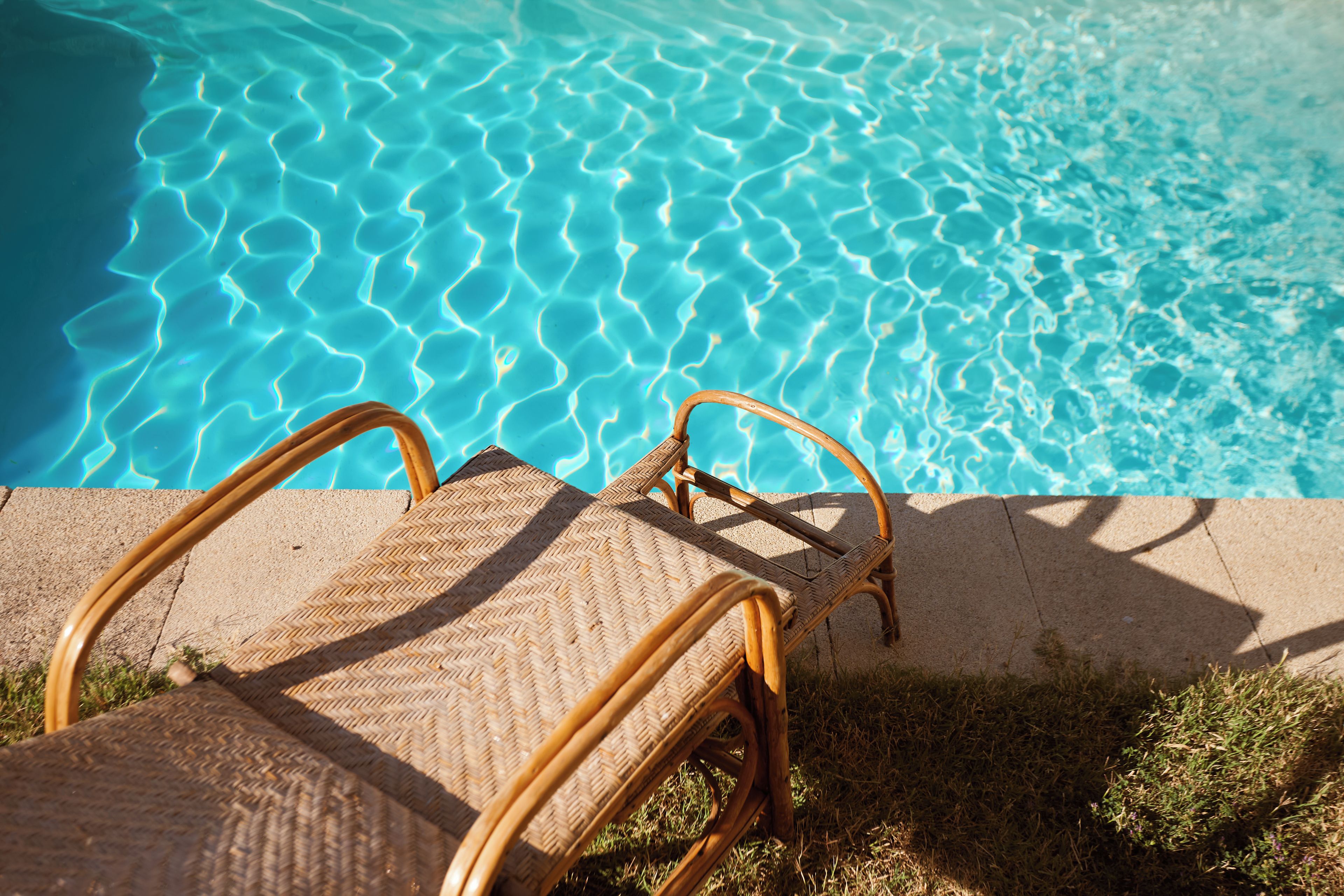 A wicker lounge chair by a clear blue pool with no visible amenities or views.