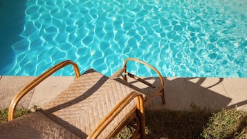 A wicker lounge chair by a clear blue pool with no visible amenities or views.