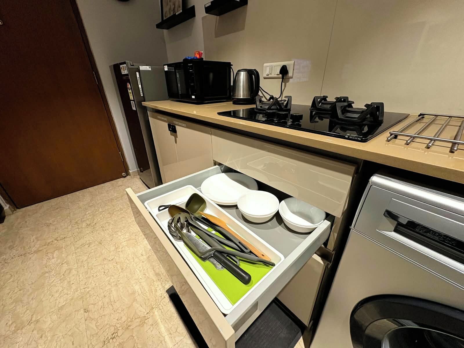 A kitchen with a countertop, a sink, a coffee maker, and a drawer with utensils.