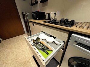 Una cocina con encimera, un fregadero, cafetera y un cajón con utensilios.