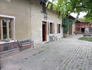 Une cour pavée de pierres, avec des bancs et un mur en pierre.