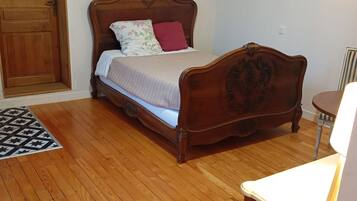 Un lit en bois avec une tête de lit, une table de chevet et une lampe fixée au mur.