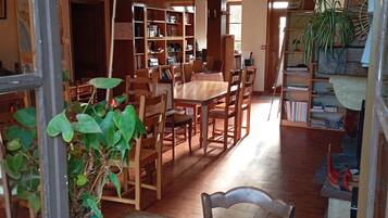 Une pièce comprenant une table à manger en bois, des chaises, une bibliothèque et une plante en pot.