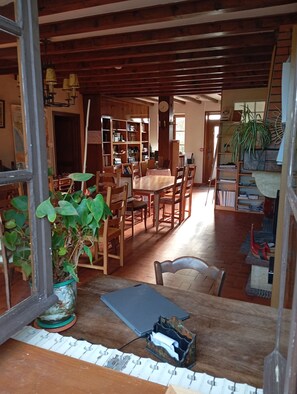 Une pièce comprenant une table à manger en bois, des chaises, une bibliothèque et une plante en pot.