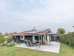 Ein Haus mit Terrasse, Gartenmöbeln und einer Solaranlage.