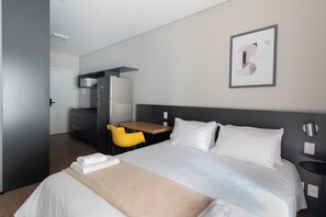 A hotel room with a bed, a desk, a chair, a wardrobe, and a bathroom. - Moura by Bhomy (São Paulo)