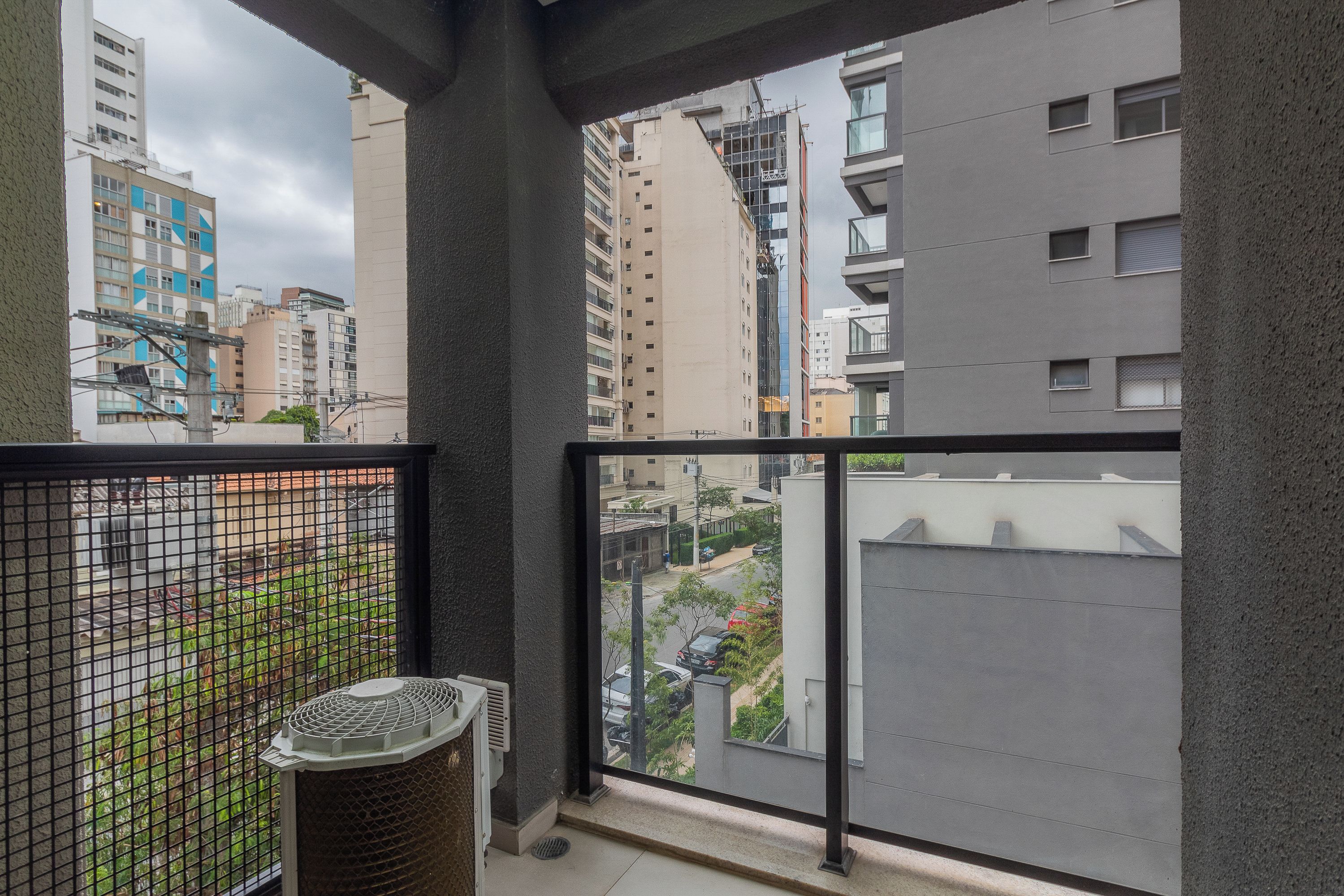 Un balcón con vista a edificios circundantes y un contenedor de basura.