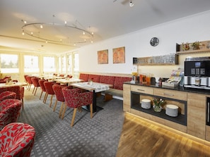 A dining area with red patterned chairs, a wooden bench, and a coffee station with a coffee machine. - Holiday Apartment With 1 Bedroom (Willingen)