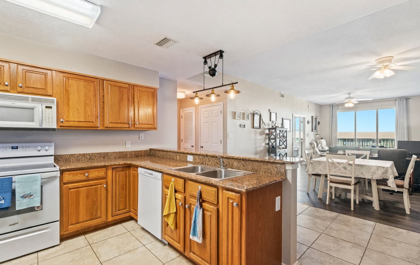 A modern kitchen with wooden cabinets, a granite countertop, and a built-in dishwasher.
