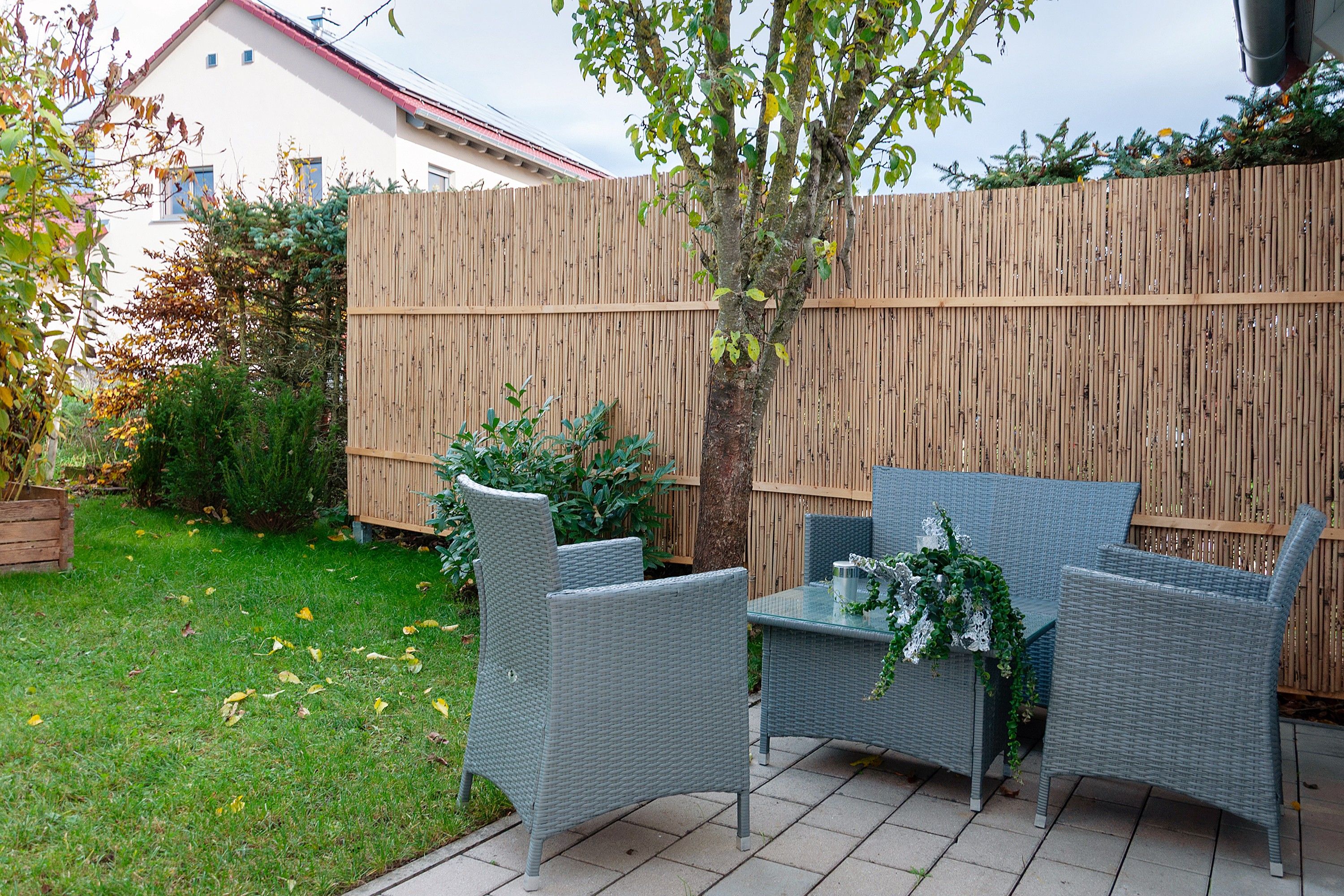 An outdoor patio area with wicker furniture and a wooden fence.