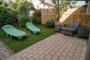 A patio with two lounge chairs, a small table, and a wooden fence. - Apartment 'TeoS' with Shared Terrace and Wi-Fi (Geslau)