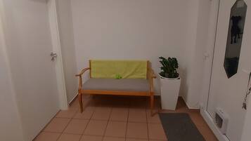A hallway with a bench, a potted plant, and a door.