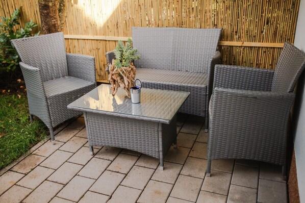 A wicker outdoor seating area with a glass table and chairs.