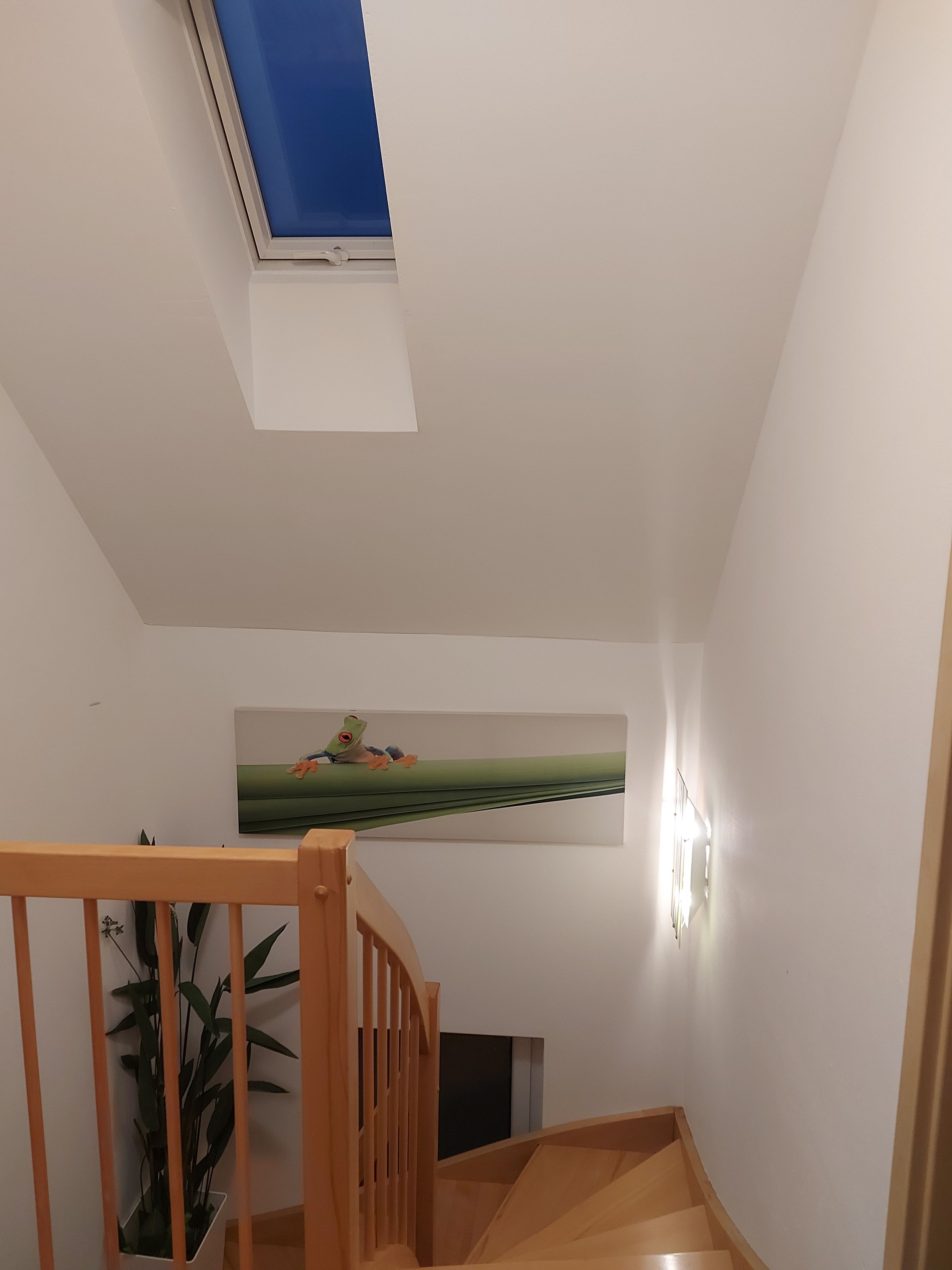 En trappe med trægelændere fører op til en platform med en vægmonteret lampe.