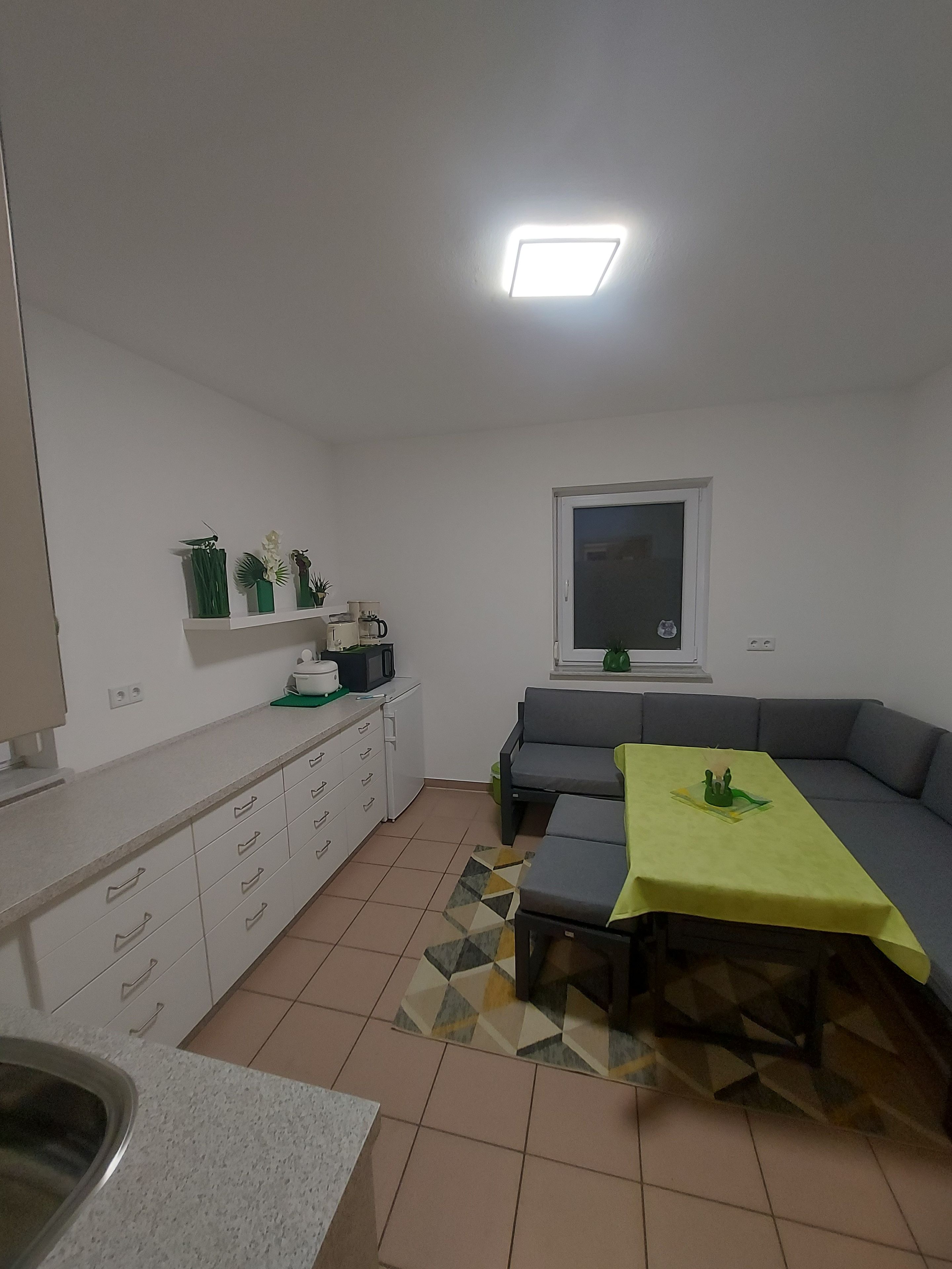A compact living space with a kitchenette, a dining area with a table and bench, and a window with a view.