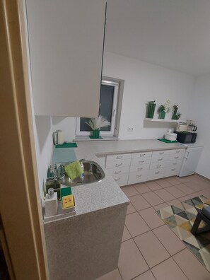 A compact kitchen with a built-in sink, a window, and a countertop with various items. - Apartment 'TeoS' with Shared Terrace and Wi-Fi (Geslau)
