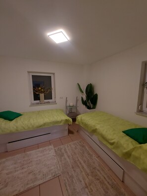Una habitación con dos camas, una ventana con vistas, una planta y una luz nocturna.