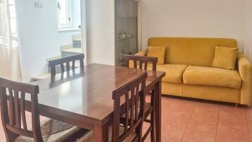 A dining area with a wooden table and chairs, a yellow sofa, and a cabinet.