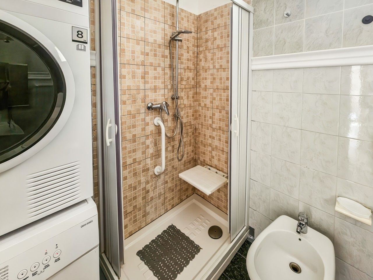 A bathroom with a shower, a toilet, and a washing machine.