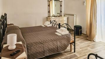 Una camera d'albergo con un letto, un comodino, una lampada e uno specchio.