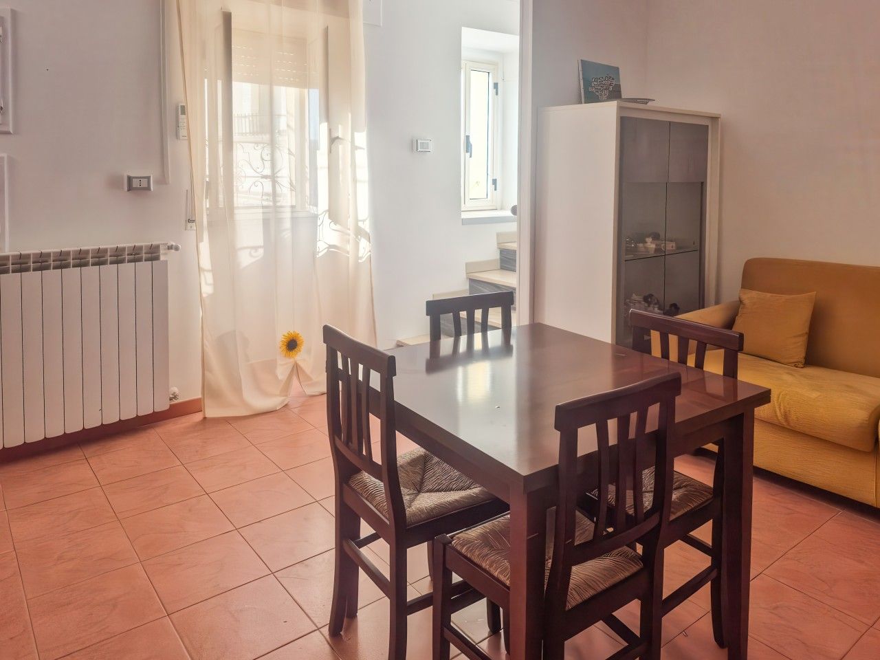 Un comedor con mesa y sillas, un sofá, un radiador y un armario.