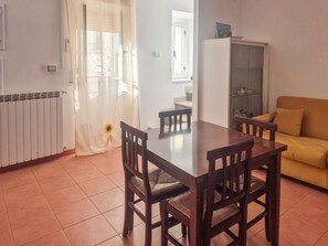 A dining area with a table and chairs, a sofa, a radiator, and a cabinet.
