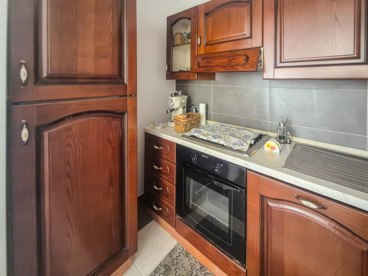 Una cocina con armarios de madera, horno empotrado y una encimera con cafetera.