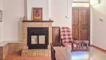 Una habitación con chimenea, un sillón escocés y una puerta de madera.