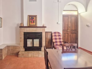 Una habitación con chimenea, un sillón escocés y una puerta de madera.