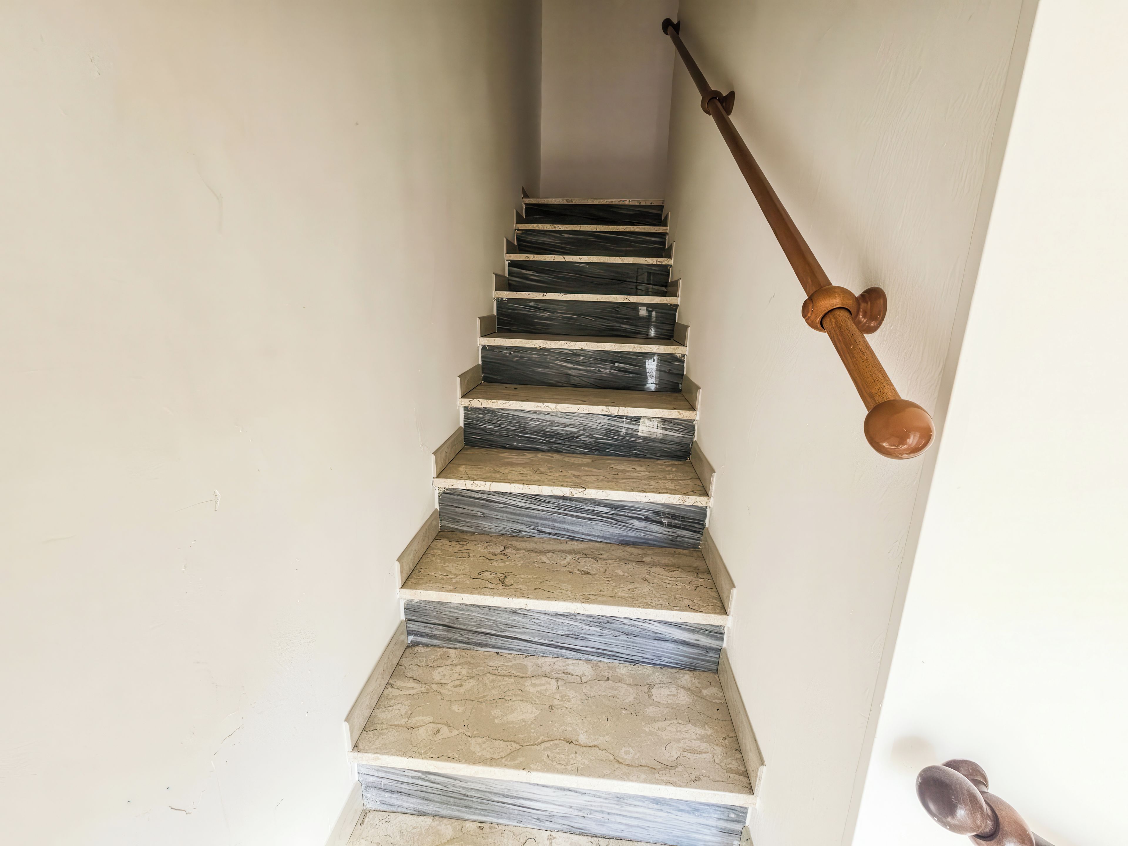 A staircase with marble steps and wooden handrails.
