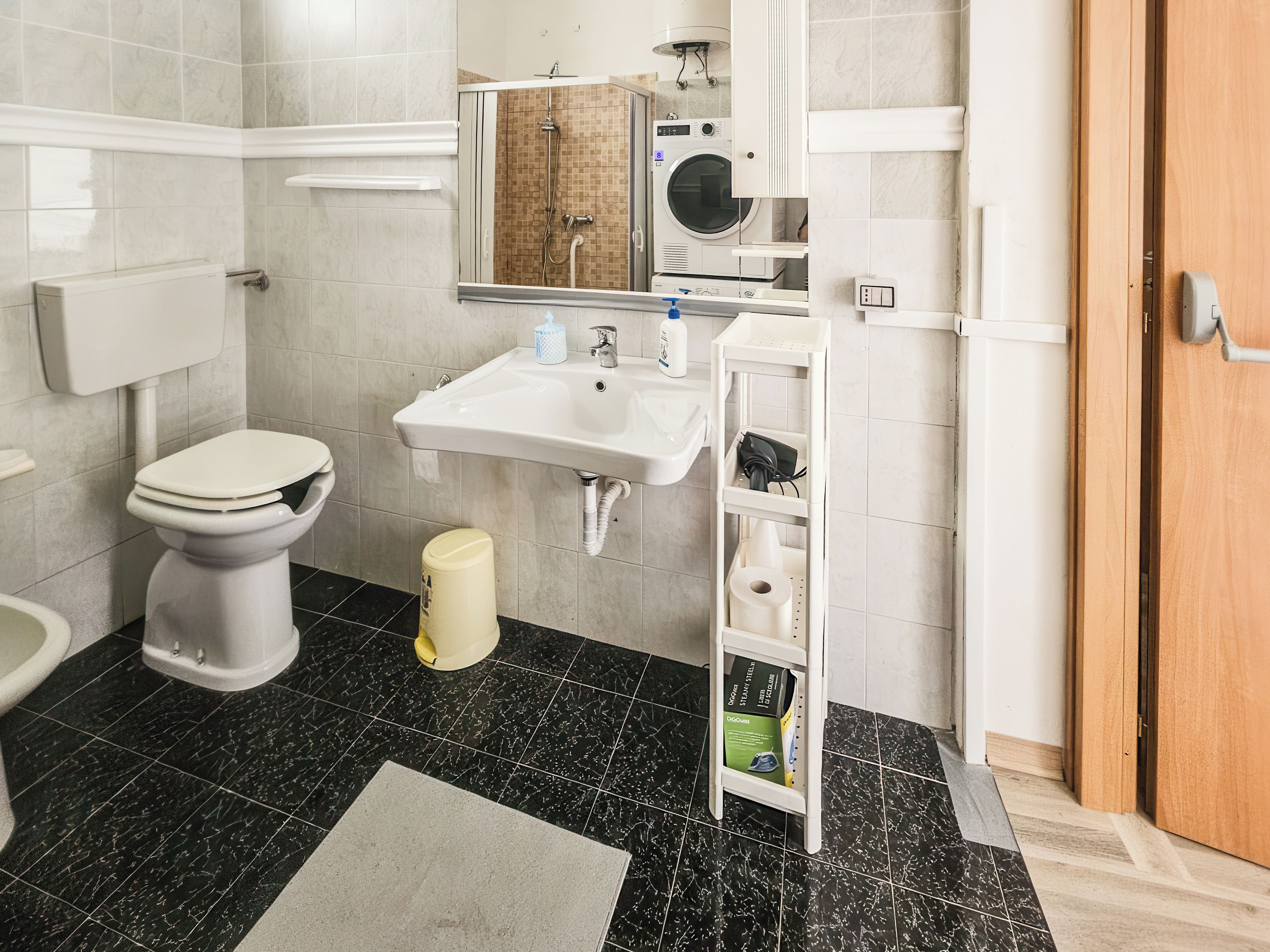 Un baño con inodoro, lavamanos y zona de ducha.
