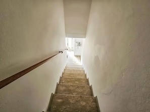 Un escalier étroit avec une rampe en bois menant à un palier.