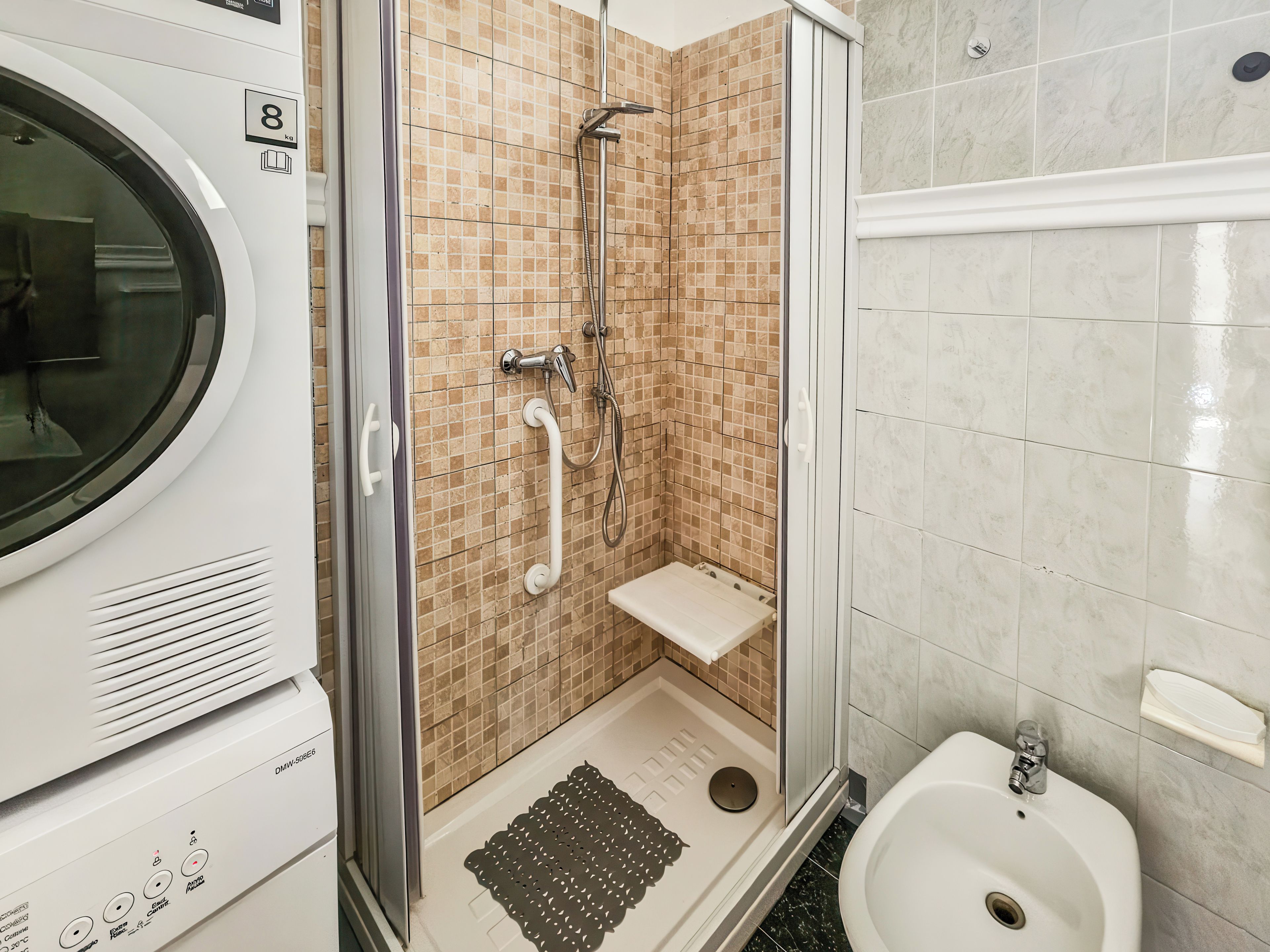 A bathroom with a shower, a toilet, and a washing machine.