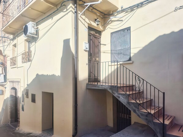 A residential building with a staircase, a door, and an air conditioning unit.