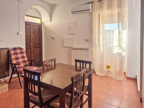 Un comedor con mesa y sillas de madera, un radiador y una ventana con cortinas.