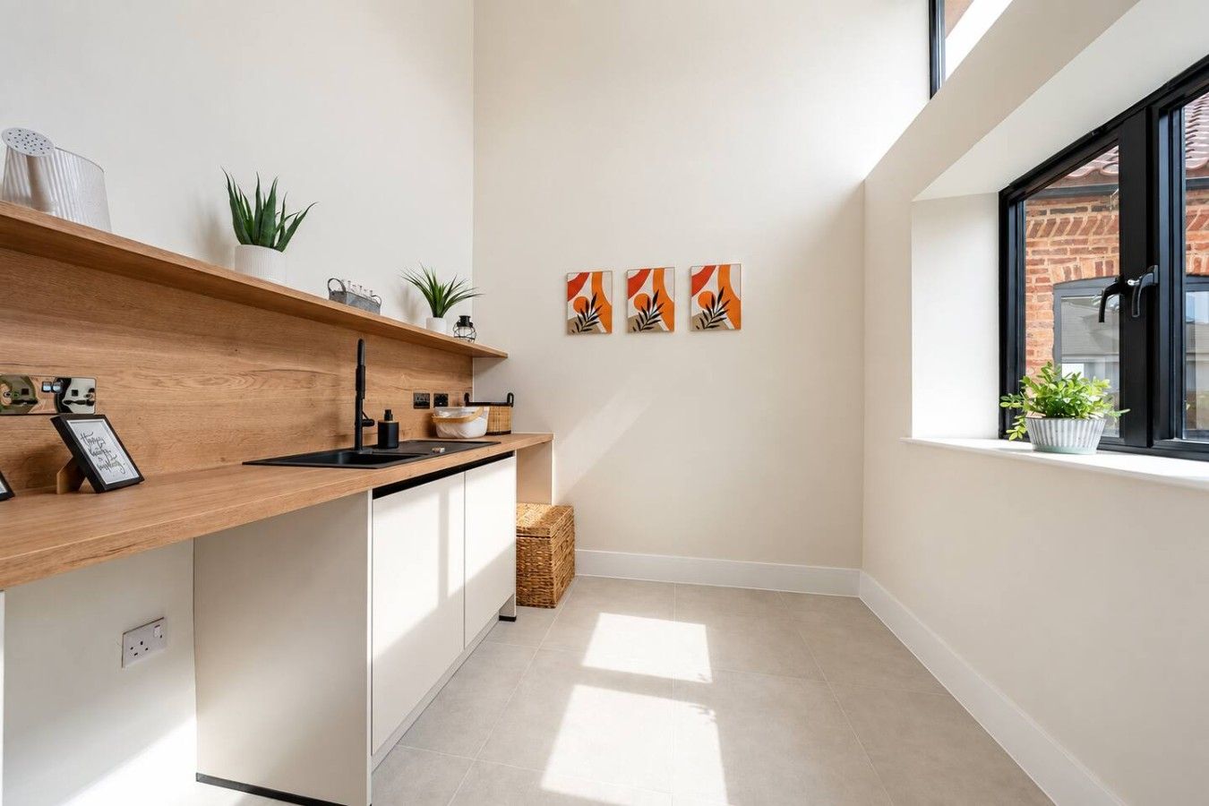 A modern kitchen with a wooden countertop, white cabinets, and a window with a view of a brick building.