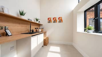 A modern kitchen with a wooden countertop, white cabinets, and a window with a view of a brick building.