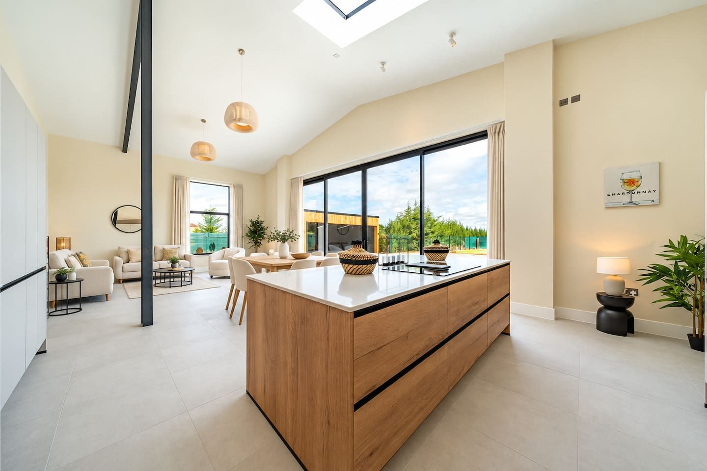 A spacious living area with a large island, a dining table, and a view of the outdoors.