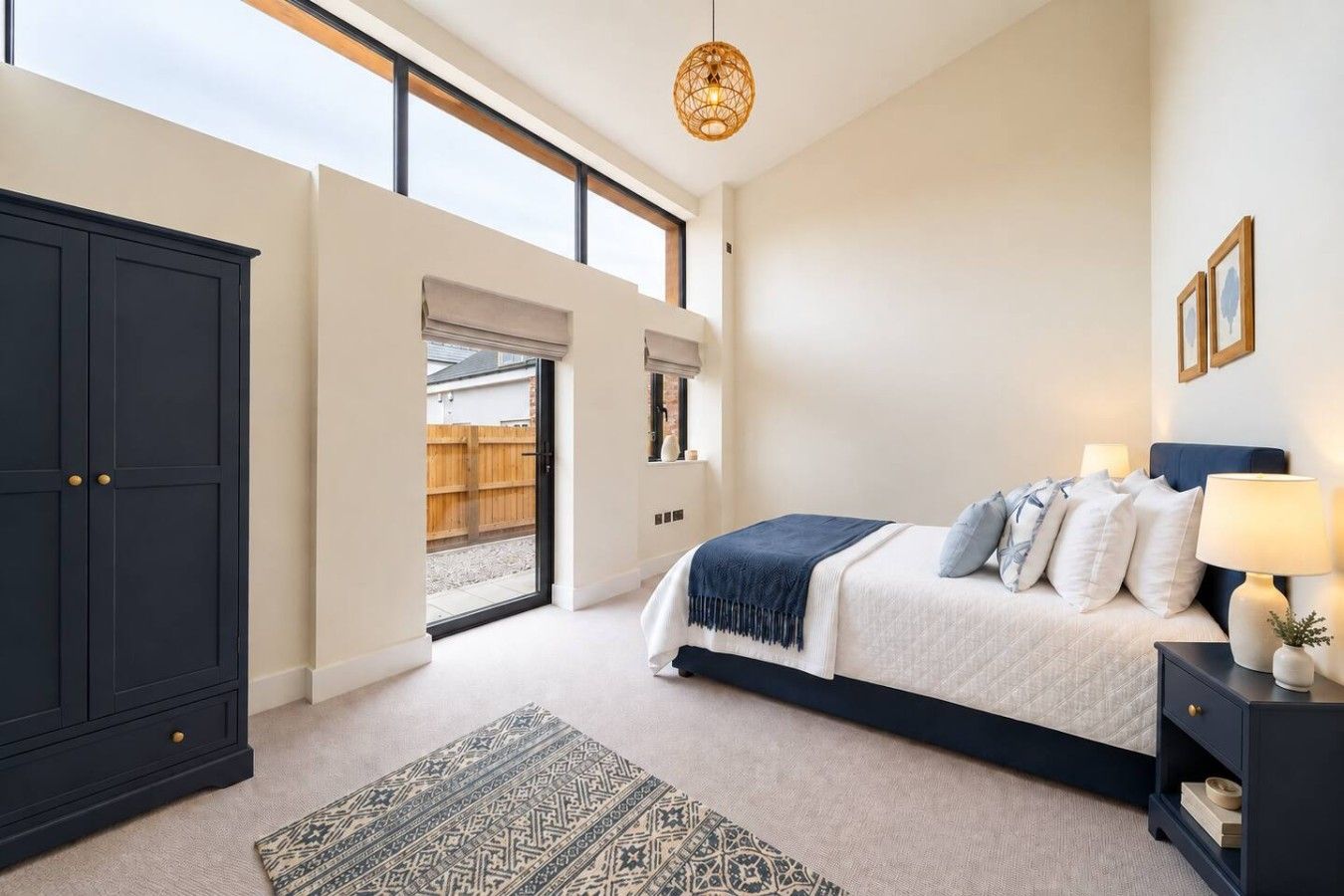 Ein Schlafzimmer mit einem Bett, Nachttischen, einem Kleiderschrank und Blick durch eine Tür nach draußen.