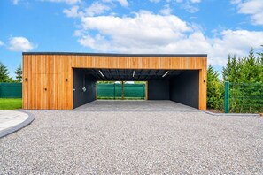 A covered outdoor area with a gravel floor and a wooden structure with a flat roof.