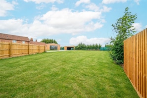 Ein Garten mit Holzzaun, Rasen und einem Gebäude mit Garage.
