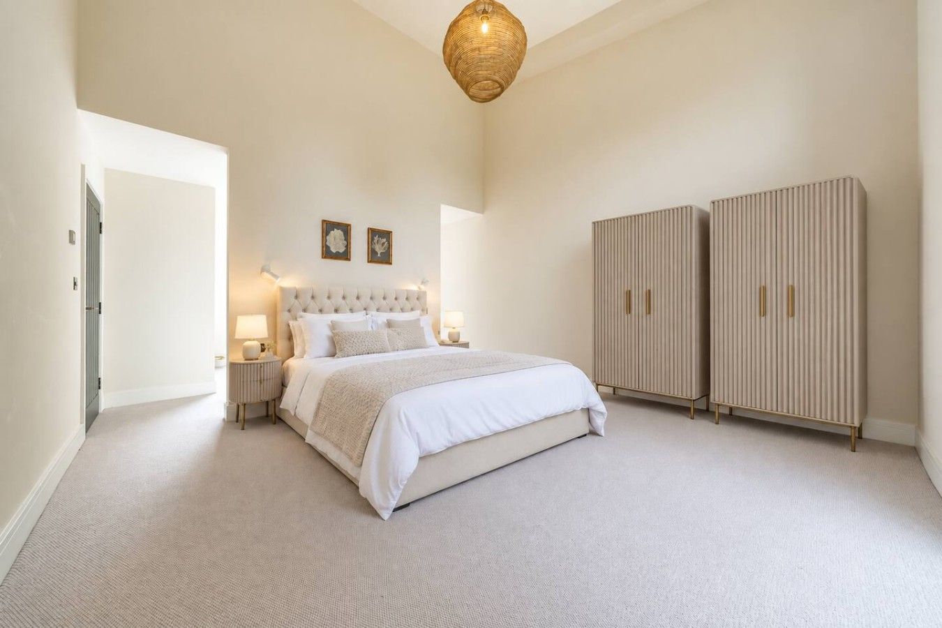 A bedroom with a large bed, bedside lamps, a wardrobe, and a ceiling light fixture.