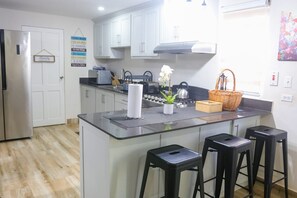 Eine moderne Küche mit einer zentralen Kochinsel, Barhocker, einem Kühlschrank und einem dekorativen Schild an der Wand.