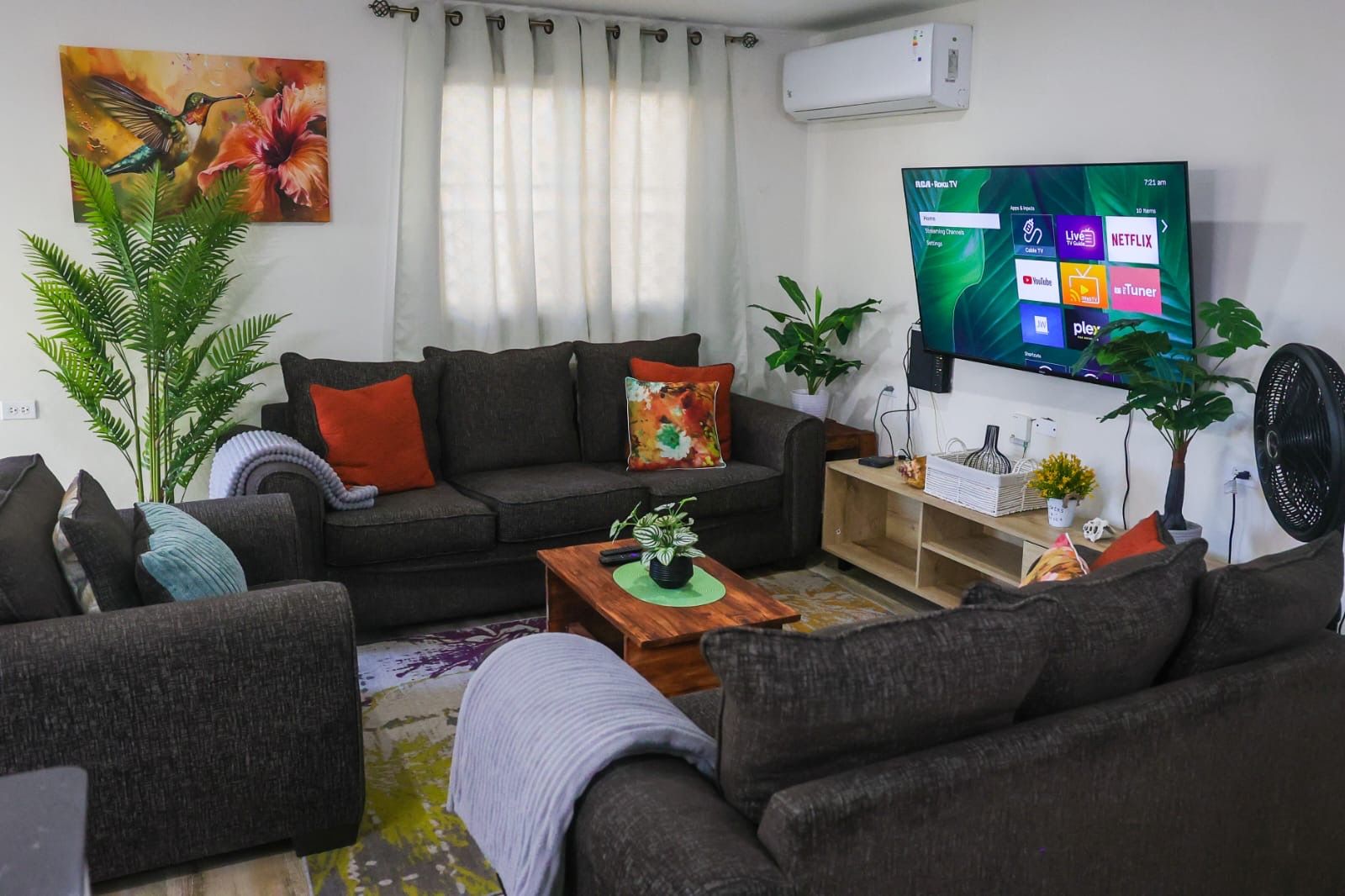 A living room with a sofa, coffee table, and a flat-screen TV mounted on the wall.