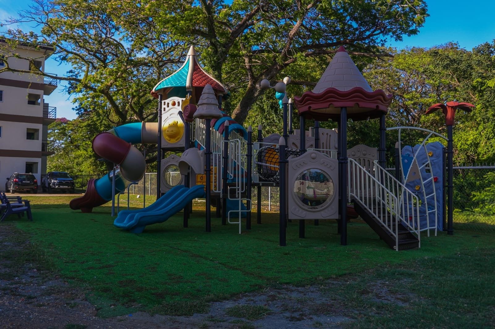 A playground with a slide, climbing structures, and a small tower.