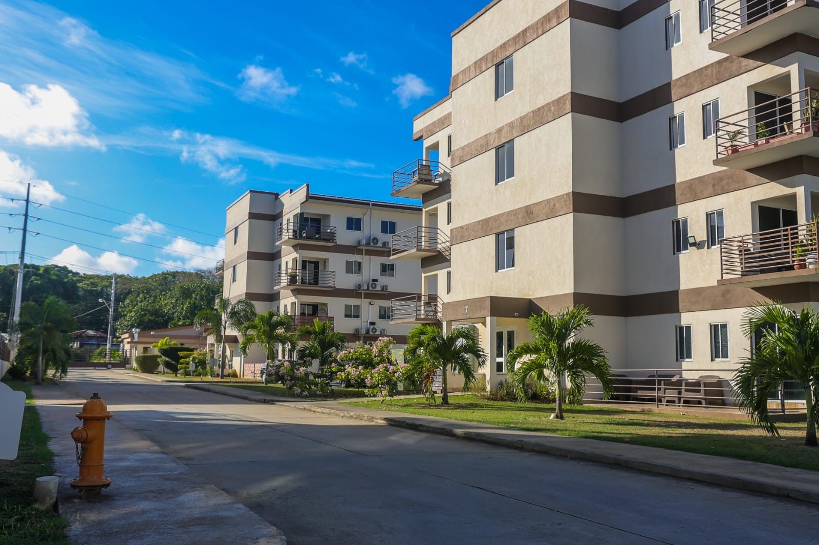 A multi-story residential building with balconies, a fire hydrant, and a clear sky.