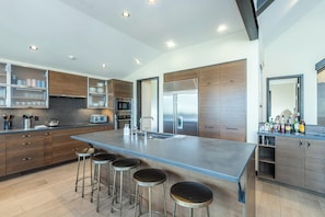 A modern kitchen with a large island, bar stools, stainless steel appliances, and a wine rack. - Canyon View Escape 6 bedrooms sleeps 16 (Telluride)