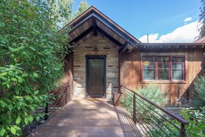 A wooden cabin with a stone entrance, a wooden deck, and a metal railing. - Canyon View Escape 6 bedrooms sleeps 16 (Telluride)