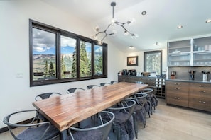 A modern kitchen with a large wooden table and chairs, a view of mountains through large windows, and a chandelier. - Canyon View Escape 6 bedrooms sleeps 16 (Telluride)