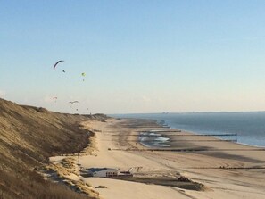 Eine Küstenlandschaft mit Sandstrand, einem kleinen Gebäude und wolkenlosem Himmel.